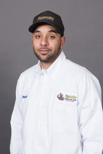 Man wearing a black cap and white work shirt with embroidered Squeaks logo and the name "Perez," standing against a plain gray background.