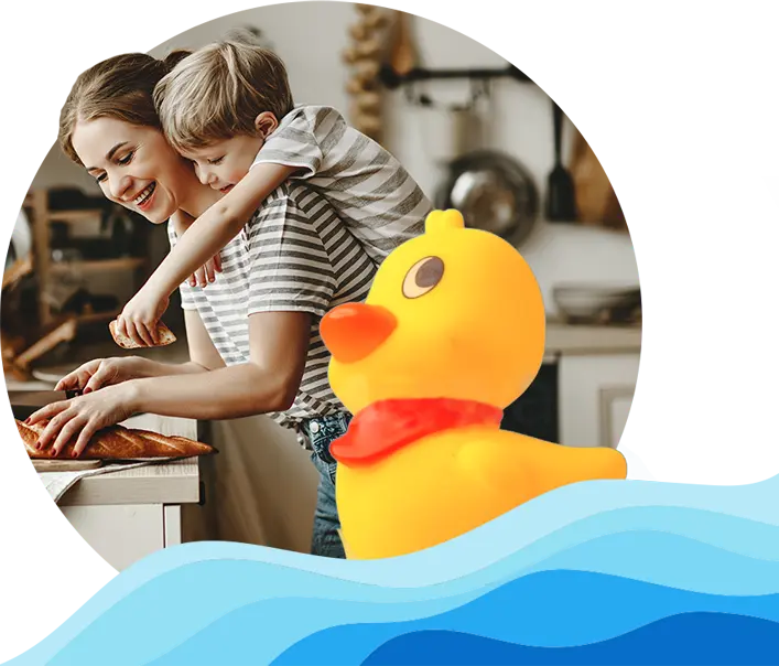 A woman slices bread in a kitchen while a child hugs her from behind; a large cartoon rubber duck with a red scarf is in the foreground, framed by blue waves.