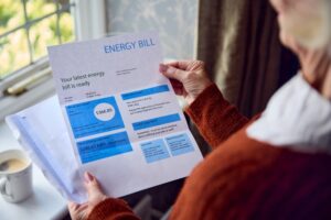 Older woman holding energy bill in her house