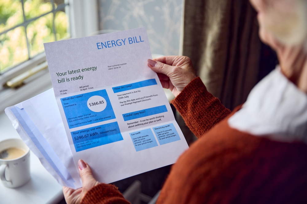 Older woman holding energy bill in her house