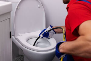 Squeak's plumber inserting hydro jet into the toilet to clean the drains.