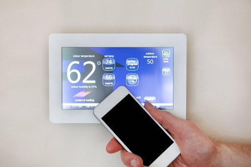 iPhone being held up to smart thermostat.