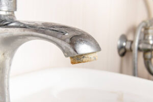 Faucet aerator shows limescale buildup from hard water.