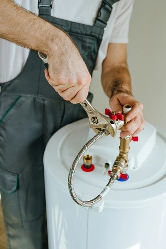 Man fixing water heater. Close-up view of male hands using wrench.