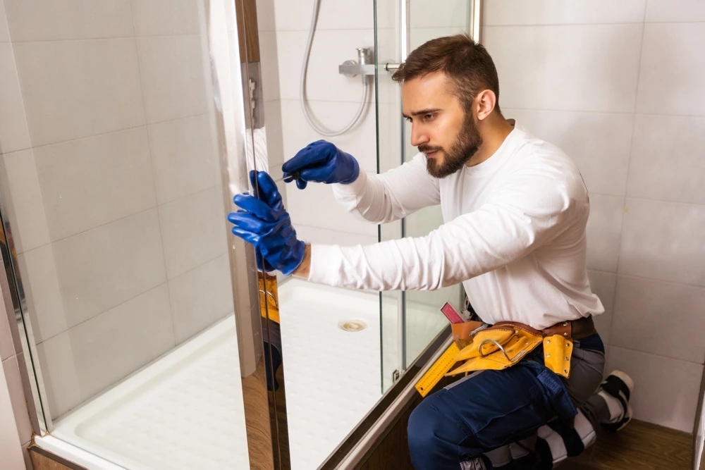Plumber installing a shower cabin in bathroom